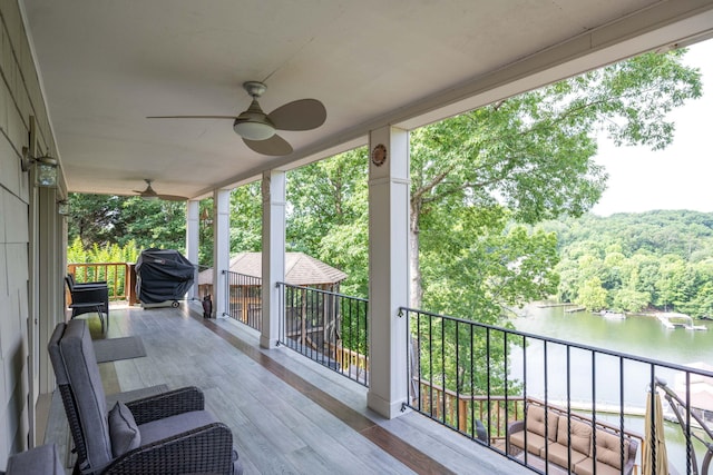 wooden deck with ceiling fan, grilling area, and a water view