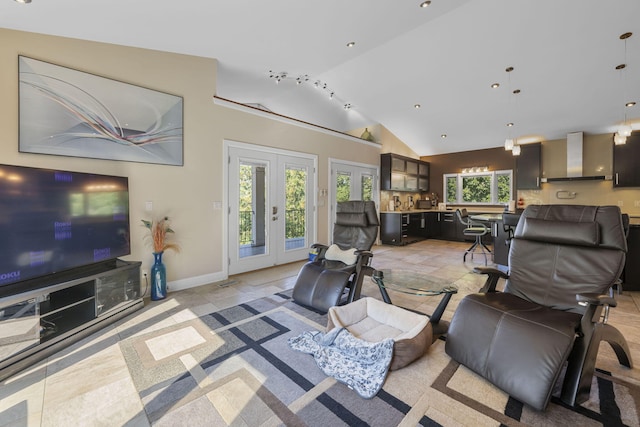 living room featuring french doors, vaulted ceiling, a chandelier, and a healthy amount of sunlight