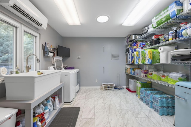 laundry room with an AC wall unit, washing machine and clothes dryer, and sink