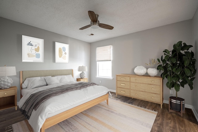 bedroom featuring ceiling fan, dark hardwood / wood-style floors, and a textured ceiling