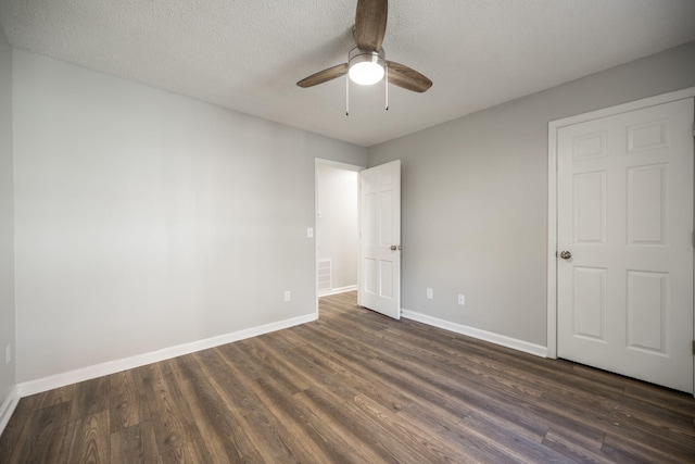 unfurnished bedroom with a textured ceiling, dark hardwood / wood-style flooring, and ceiling fan