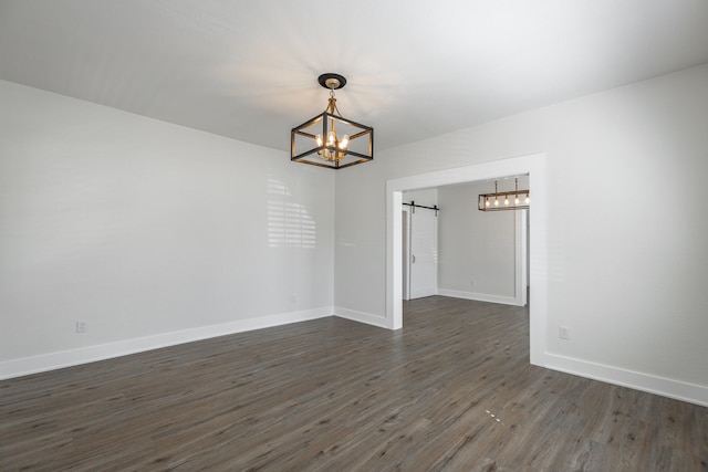 unfurnished dining area featuring a barn door, an inviting chandelier, and dark hardwood / wood-style flooring