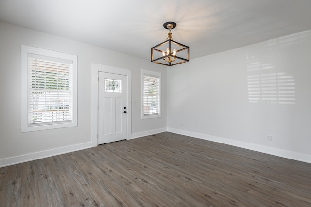 foyer featuring an inviting chandelier, plenty of natural light, and dark wood-type flooring