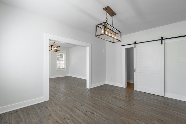 unfurnished dining area featuring a notable chandelier, dark hardwood / wood-style floors, and a barn door