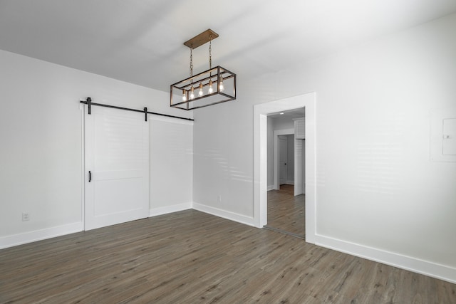 unfurnished dining area with dark hardwood / wood-style flooring, an inviting chandelier, and a barn door