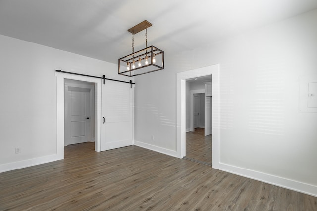 unfurnished dining area with dark hardwood / wood-style floors and a barn door