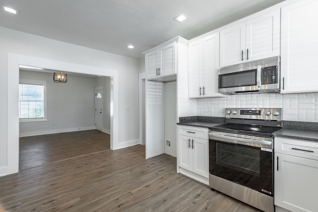 kitchen with appliances with stainless steel finishes, backsplash, white cabinetry, and dark hardwood / wood-style floors