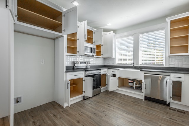 kitchen featuring dark hardwood / wood-style floors, tasteful backsplash, sink, white cabinets, and stainless steel appliances