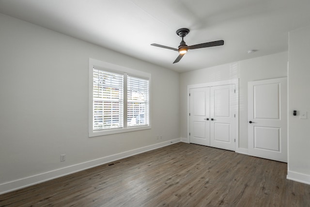 unfurnished bedroom featuring ceiling fan, a closet, and dark wood-type flooring