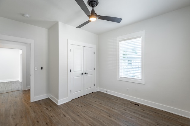 unfurnished bedroom featuring a closet, ceiling fan, and dark wood-type flooring