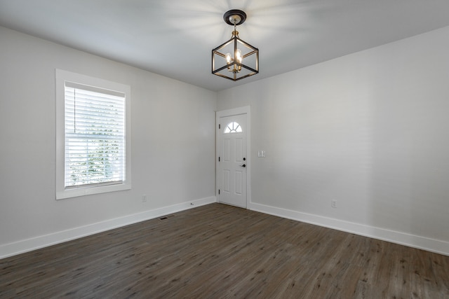 foyer entrance with dark hardwood / wood-style floors and a chandelier