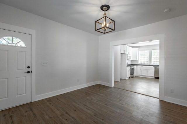 interior space with a notable chandelier, plenty of natural light, and dark wood-type flooring