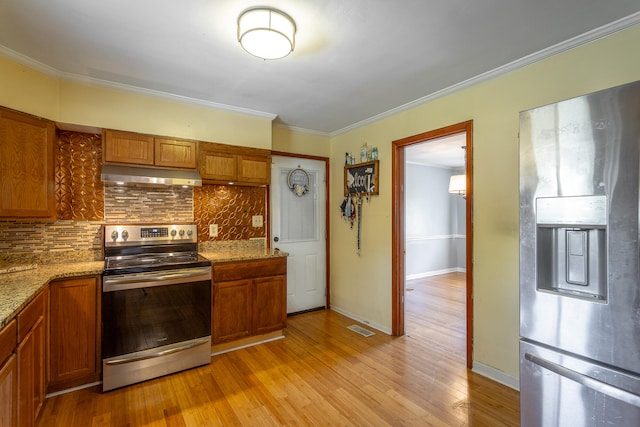 kitchen with tasteful backsplash, light stone counters, light hardwood / wood-style flooring, ornamental molding, and appliances with stainless steel finishes