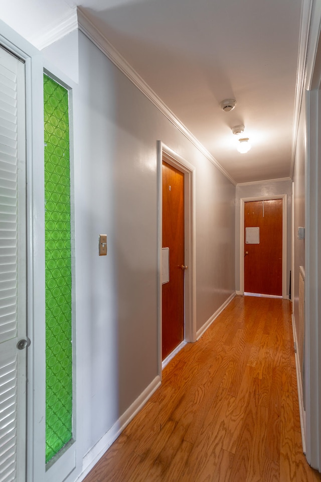 hall with ornamental molding and light hardwood / wood-style floors