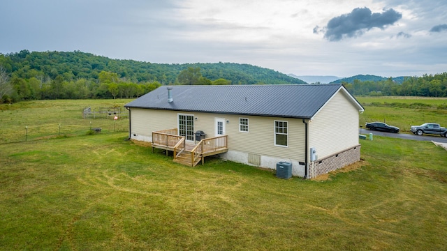 back of property with a yard, a deck with mountain view, and central AC unit