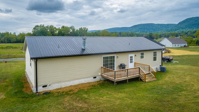 rear view of house with a lawn, a deck with mountain view, and central AC unit