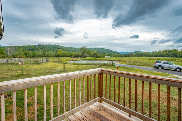 wooden terrace featuring a rural view and a yard