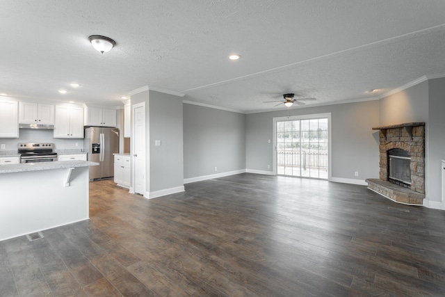 unfurnished living room with ceiling fan, dark hardwood / wood-style flooring, crown molding, a textured ceiling, and a fireplace