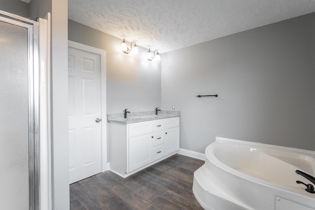 bathroom with vanity, a textured ceiling, hardwood / wood-style flooring, and a bathing tub