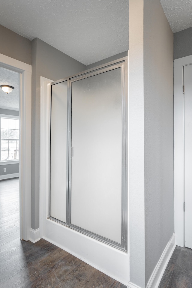 bathroom featuring an enclosed shower, wood-type flooring, and a textured ceiling