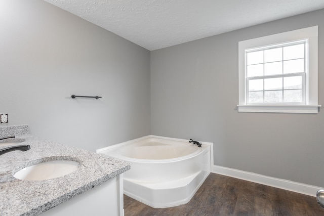 bathroom featuring a textured ceiling, vanity, a bath, and hardwood / wood-style floors