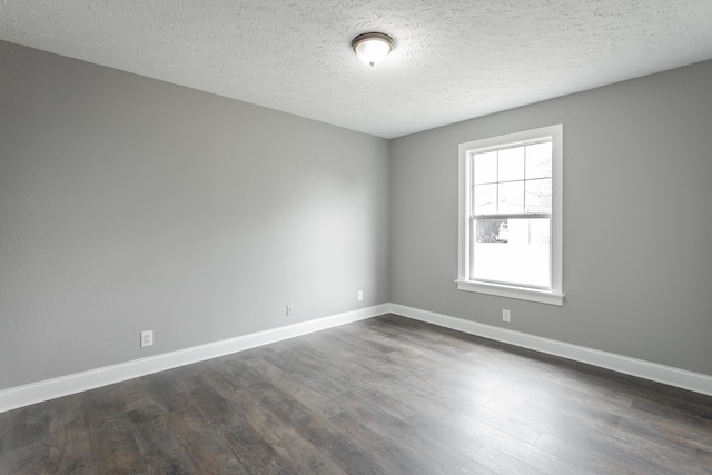 spare room featuring dark hardwood / wood-style floors and a textured ceiling