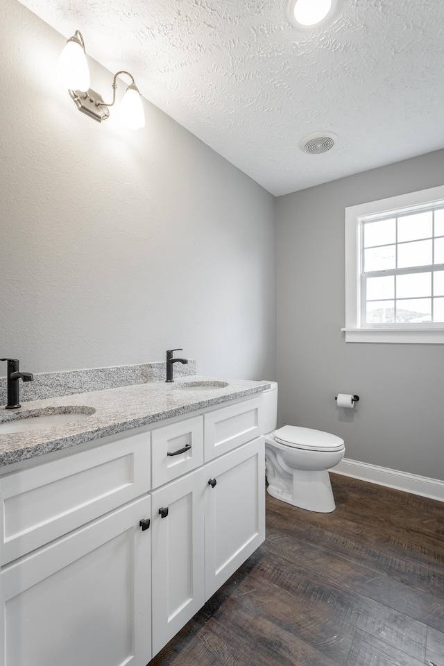 bathroom with hardwood / wood-style floors, vanity, toilet, and a textured ceiling