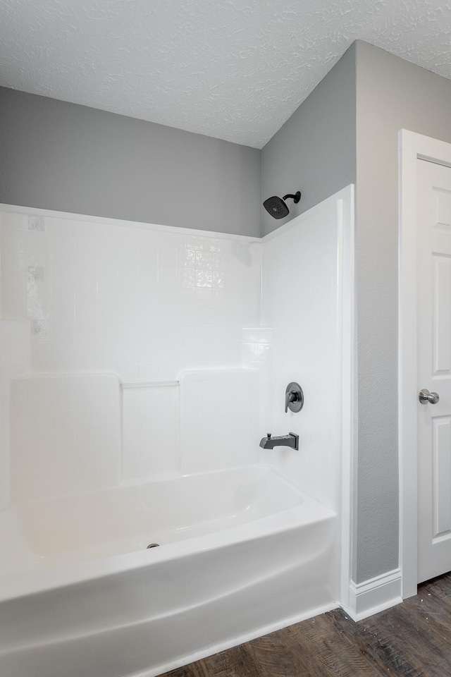 bathroom with hardwood / wood-style floors, shower / bathtub combination, and a textured ceiling