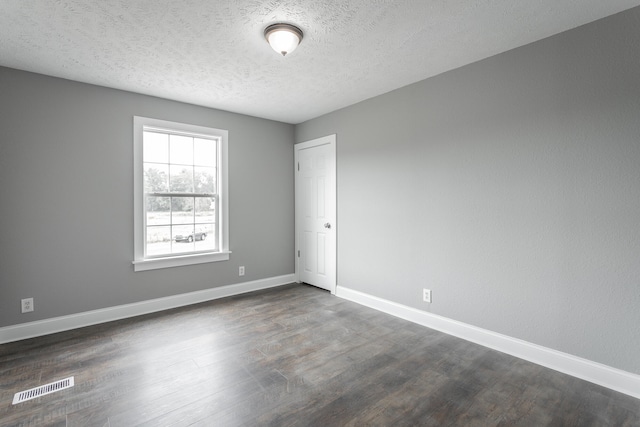 spare room featuring dark hardwood / wood-style flooring and a textured ceiling