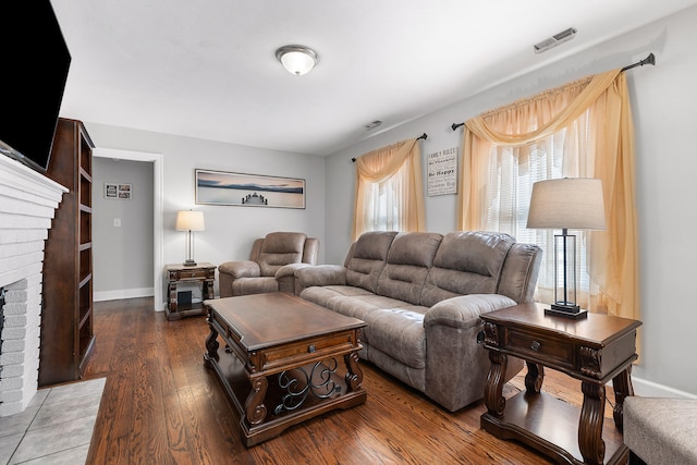 living room featuring a brick fireplace and dark hardwood / wood-style floors