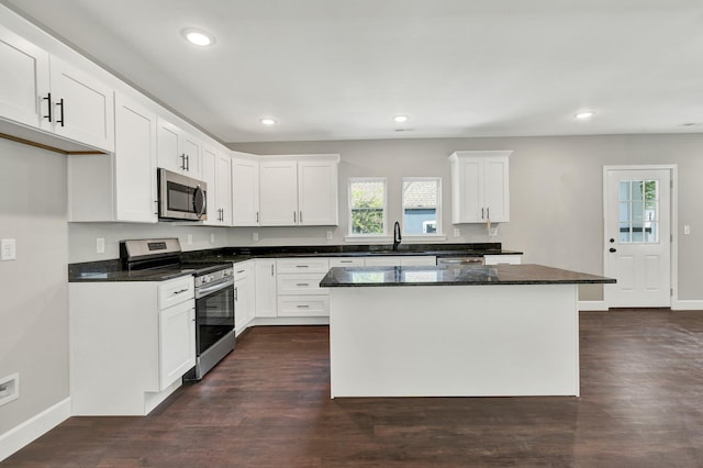 kitchen with appliances with stainless steel finishes, a center island, sink, and white cabinetry