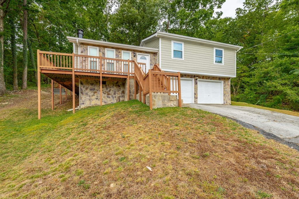 view of front facade featuring a wooden deck, a garage, and a front yard