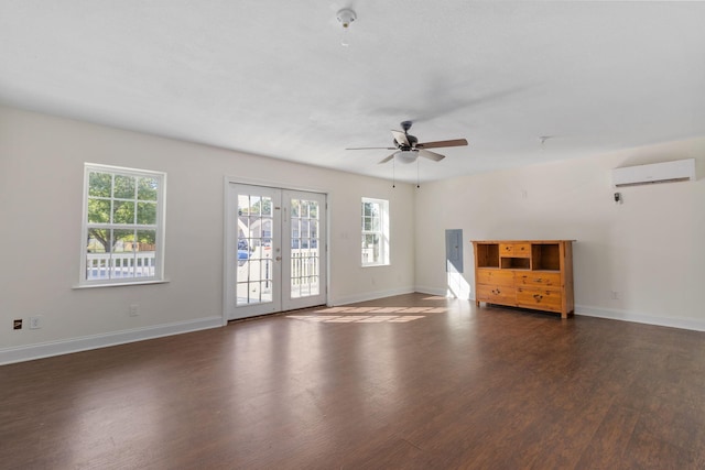 unfurnished living room with an AC wall unit, dark hardwood / wood-style floors, ceiling fan, and french doors