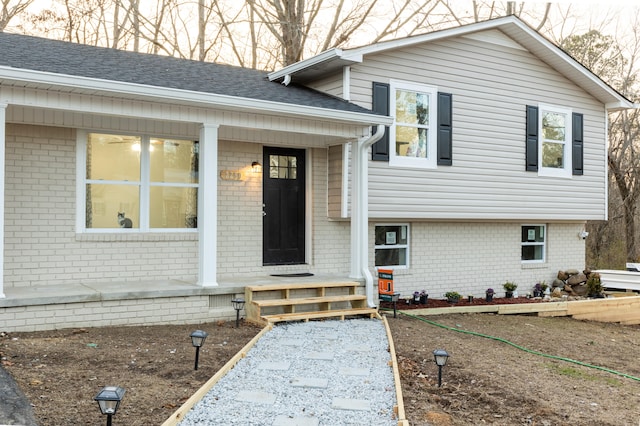 tri-level home with brick siding and a shingled roof