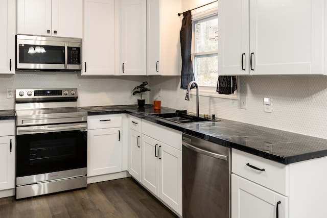 kitchen with tasteful backsplash, dark hardwood / wood-style flooring, white cabinetry, sink, and stainless steel appliances