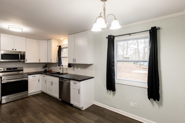 kitchen featuring appliances with stainless steel finishes, a wealth of natural light, decorative light fixtures, and white cabinets