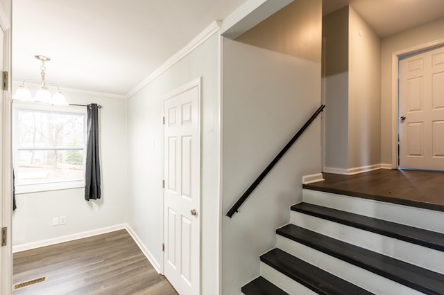 stairway featuring baseboards, wood finished floors, visible vents, and ornamental molding