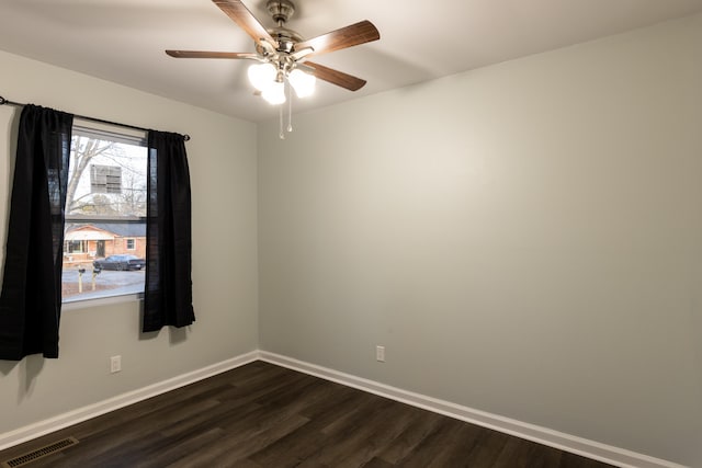 unfurnished room featuring dark wood finished floors, visible vents, a ceiling fan, and baseboards