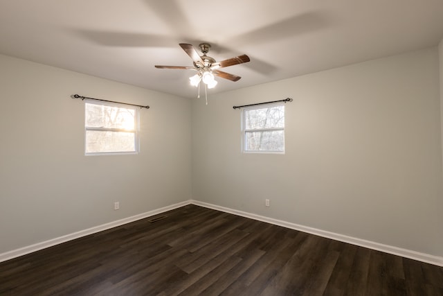 unfurnished room featuring a healthy amount of sunlight, dark wood-type flooring, and ceiling fan