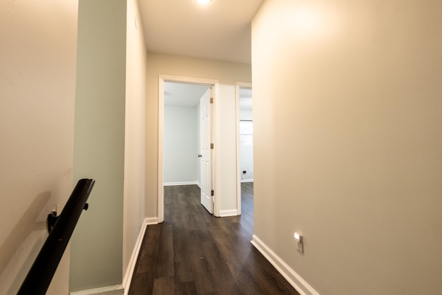 hall with baseboards, dark wood-style floors, and an upstairs landing