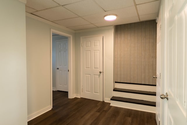 hall featuring baseboards, dark wood-style flooring, and a paneled ceiling