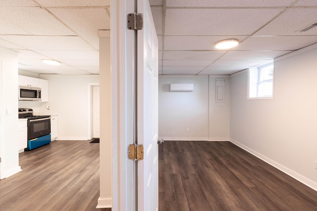 below grade area featuring dark wood-type flooring, a wall mounted AC, visible vents, and a drop ceiling