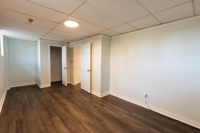 basement with dark wood-type flooring, a paneled ceiling, visible vents, and baseboards