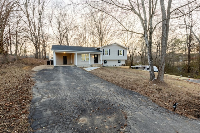 tri-level home with aphalt driveway, a porch, and an attached carport
