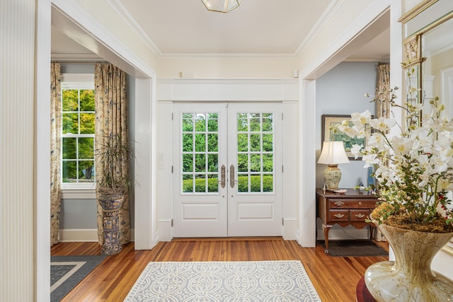 entrance foyer with french doors, plenty of natural light, hardwood / wood-style floors, and crown molding