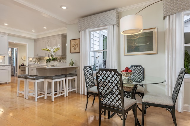 dining room with crown molding and light hardwood / wood-style floors