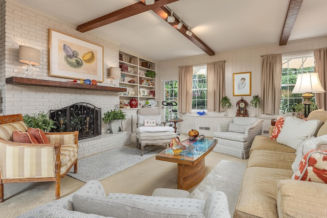 carpeted living room with beam ceiling, plenty of natural light, a fireplace, and rail lighting