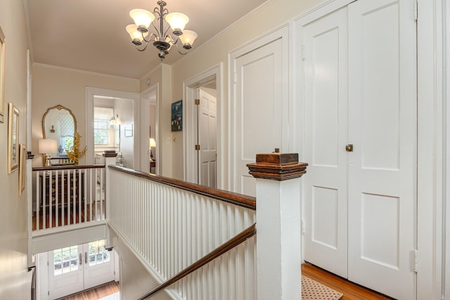 hall with crown molding, light hardwood / wood-style floors, and a chandelier