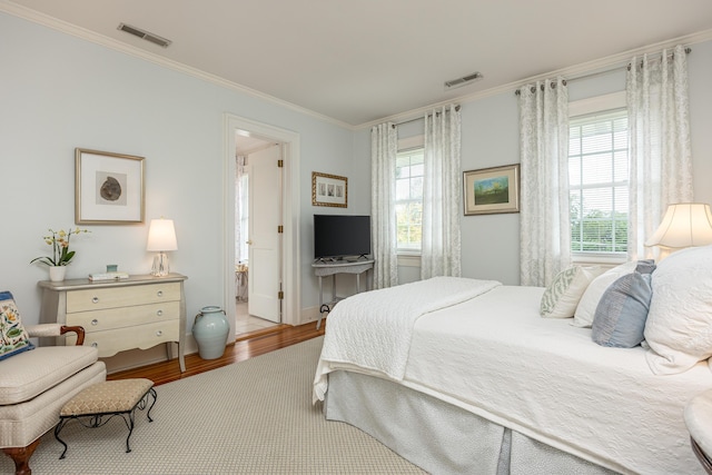 bedroom featuring multiple windows, connected bathroom, ornamental molding, and light hardwood / wood-style flooring