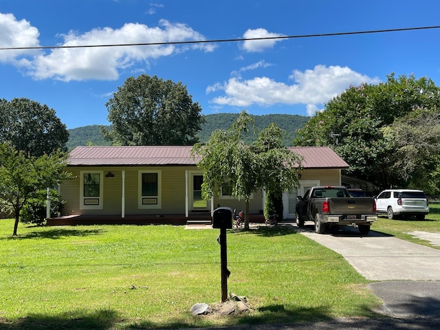 ranch-style home featuring a mountain view, a front lawn, a porch, and a garage